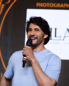 a man holding a microphone in his right hand and wearing a blue t - shirt