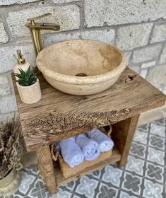 a bathroom sink sitting on top of a wooden table next to a potted plant