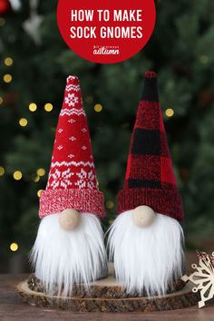 two red and white gnomes sitting on top of a wooden log next to a christmas tree