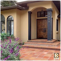 the front entrance to a home with steps leading up to it and purple flowers growing outside