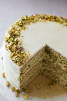 a cake with white frosting and pistachios on top