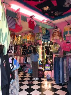 a woman standing in front of a store filled with clothing and other items on display