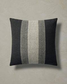 a black and white striped pillow on a gray wall