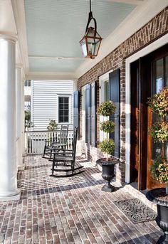 a porch with rocking chairs and potted plants