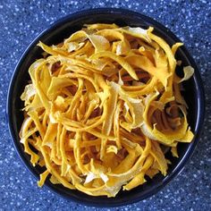 a black bowl filled with pasta on top of a blue counter