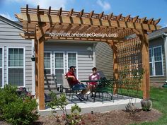 two people sitting at a table under a wooden pergoline on top of a patio