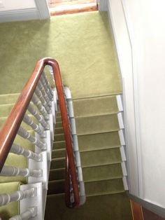 the stairs are lined with green carpet and white railings, along with wooden handrails