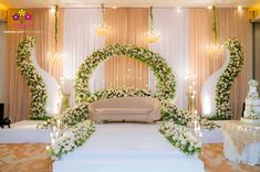 a wedding ceremony with white flowers and greenery on the stage, decorated with candles