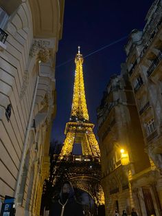 the eiffel tower lit up at night with people walking around in the foreground