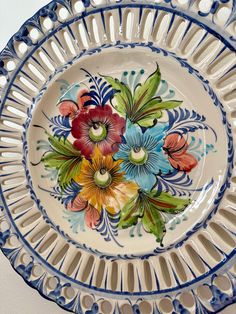 a blue and white bowl with flowers painted on the inside is hanging from a wall