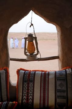 a lantern hanging from the side of a stone wall in front of a window with people walking by