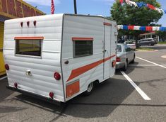 an rv parked in a parking lot next to a yellow and white building with flags