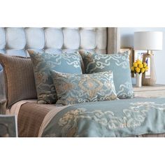 a bed with blue and gold pillows on it's headboard in a bedroom