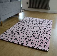 a pink rug with black and white animal print on it in front of a couch