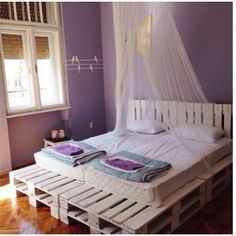 a bed made out of pallets in a room with purple walls and wooden floors