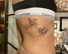 a woman's stomach with an angel tattoo on her lower back and the words canni kilnin written across it