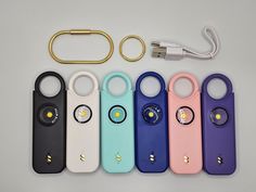 several different colored devices are sitting next to each other on a white surface with a gold keychain