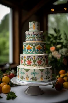 a multi layer cake sitting on top of a table next to oranges and flowers