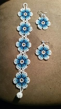 a pair of blue and white beaded earrings and earring set on top of a brown surface