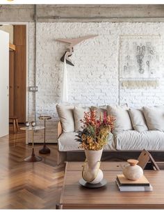 a living room filled with furniture next to a white brick wall and wooden flooring