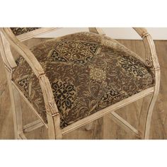 a chair with an ornate upholstered back and seat cushion on top of wood flooring