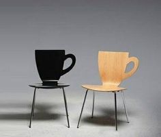 two chairs sitting next to each other in front of a gray wall and one has a black coffee cup on it