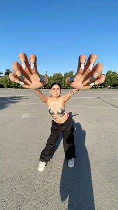 a woman standing in an empty parking lot holding up her hands