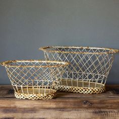 two gold wire baskets sitting on top of a wooden table