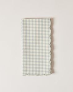 a white and blue checkered napkin with scalloped edges on a white background