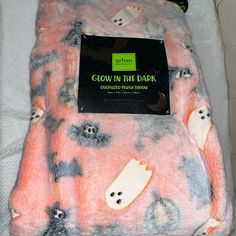 a blanket that has been wrapped in pink and black with ghost faces on it, along with a tag reading glow in the dark