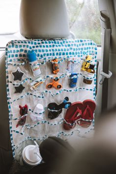 a car seat organizer with various items hanging from it's back side, in front of a window