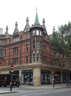 an old building with people walking on the sidewalk