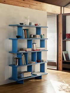 a blue shelf with books on it in a living room next to a wooden floor