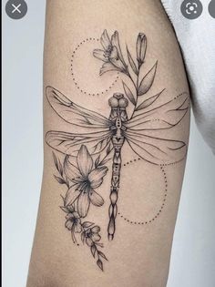 a woman's thigh with flowers and a dragonfly tattoo on the side of her leg