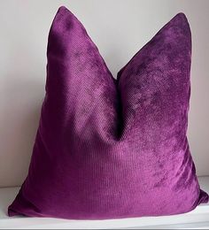 a purple pillow sitting on top of a white shelf