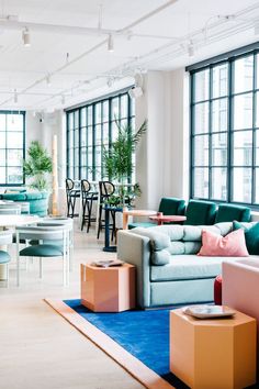 a living room filled with lots of furniture next to large windows and tables in front of them