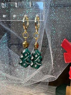 These delightful handmade dangle earrings are a festive addition to your holiday wardrobe. Featuring charming green Christmas tree charms adorned with gold stars, they evoke the magic of the season. Each earring is securely fastened with gold-plated round lever backs, ensuring comfort and elegance. Perfect for holiday parties or as a thoughtful gift, these earrings are a beautiful way to celebrate the joy of Christmas. Christmas Party Dangle Earrings, Christmas Celebration Dangle Earrings, Christmas Drop Earrings For Celebration, Green Holiday Drop Earrings, Holiday Green Drop Earrings, Christmas Celebration Drop Earrings, Green Dangle Earrings For Celebration, Elegant Green Earrings For Christmas, Green Jewelry For New Year Party