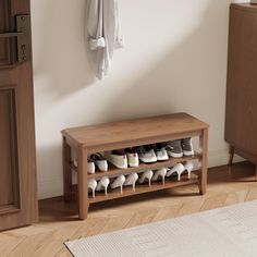 a wooden bench with shoes on it in front of a white wall and wood floor