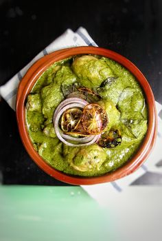 a red bowl filled with green food on top of a table