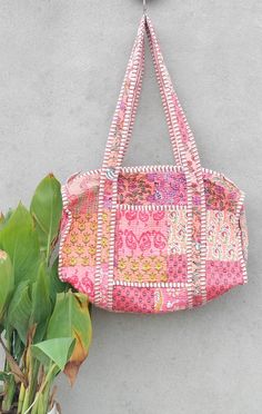 a pink bag hanging from the side of a wall next to a potted plant