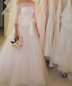 a woman in a wedding dress standing next to dresses