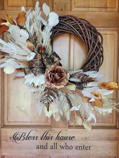 a wreath with feathers and flowers on it that says, blessing this house and all who enter