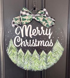 a merry christmas door hanger with pine trees and bows on it's front