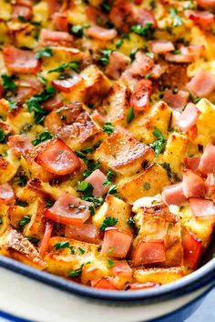 a casserole dish with ham, cheese and parsley in it on a blue and white plate