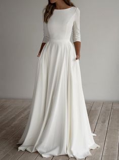 a woman in a white dress standing on a wooden floor with her back to the camera