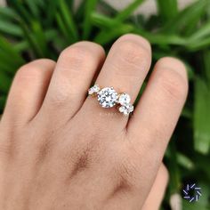 a person's hand holding a three stone ring