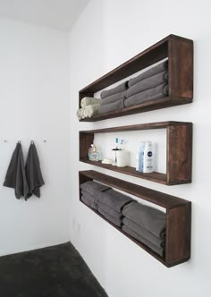 two wooden shelves holding towels and other bathroom items