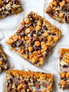 several pieces of chocolate chip cookie bars on top of a white paper towel with nuts and other toppings