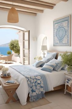 a bedroom with an ocean view is shown in this image, and the bed has blue and white linens on it