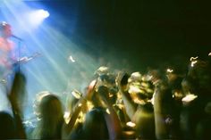 a man playing guitar on stage in front of a crowd at a music concert with bright lights